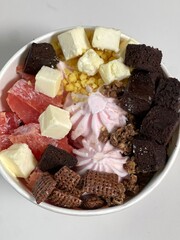 Swirled yogurt ice cream dessert served in a cup, smooth creamy texture with glossy surface, topped with fresh fruit pieces, highlighting its refreshing and inviting appearance in detail