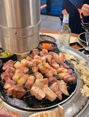 Grilled samgyeopsal, showcasing thick slices of pork belly sizzling on the grill. A popular Korean barbecue dish, capturing the essence of a delicious dining experience.