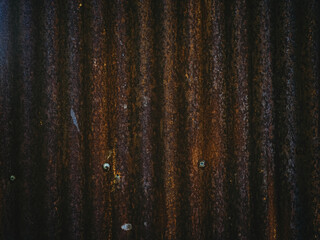 Old corrugated zinc sheet with heavy rust and weathered texture. Vintage industrial backdrop with...