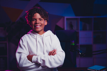 Confident teen in hoodie with microphone setup in neon lit room, portraying gamer and aspiring content creator