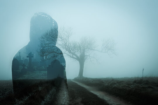 A double exposure of a spooky hooded figure, on a track in the countryside on bleak foggy winters day