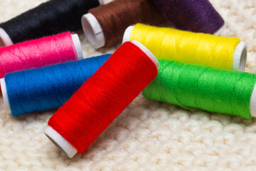 A set of colored threads for sewing on spools. A stack of multi-colored spools of thread