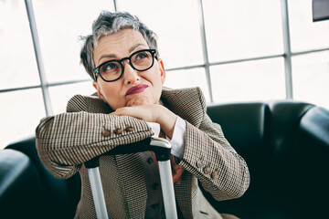 Mature businesswoman in elegant suit at office with thoughtful expression, showcasing...