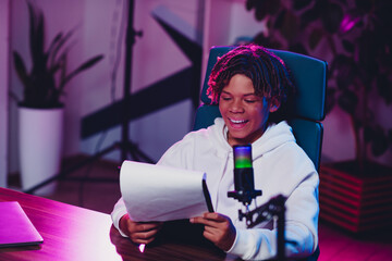 Positive Male Teenager Blogging at Home in Neon Lighting With Microphone and Camera for Streaming or Podcasting Content