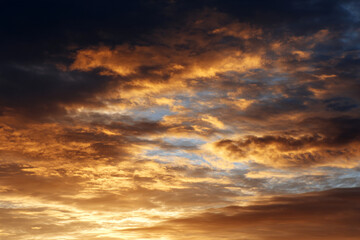 Obraz premium Golden sunrise sky with dramatic clouds, warm light and peaceful atmosphere, perfect for nature and landscape backgrounds