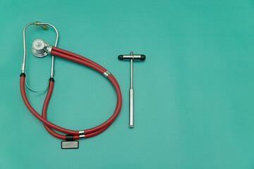 red stethoscope and medical hammer on green Background, Space for Text, Space for Logo