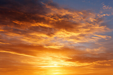 Obraz premium Bright golden sky at sunrise with dramatic clouds, warm sunlight, and peaceful atmosphere, perfect for nature and landscape backgrounds