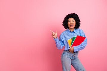 Energetic young student holding colorful notebooks and smiling on a vibrant pink background,...