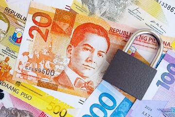 Philippines peso currency money bills and padlock close up. The concept of sanctions and financial...