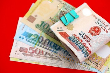 Vietnamese dong money bills in big amount close up on red. Finance and banking concept