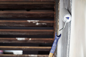 Construction worker using a paint roller to apply paint to a wall during home renovation. Home renovation project