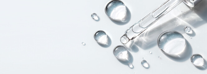 glass pipette with serum drop on light background with soft sunlight and shadows