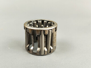 Damage a needle roller bearing is seen on a gray surface. The photo highlights the mechanical...