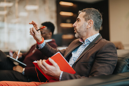 Business professional expressing ideas during a team discussion or meeting. Collaborative work environment with team members present.