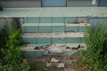 Damaged old floor stairs with green ceramic plates.