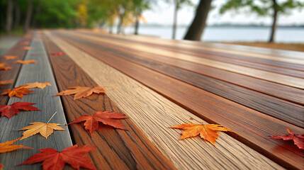 Autumn leaves lying on a wooden bench near a lake in a peaceful nature setting during golden hour