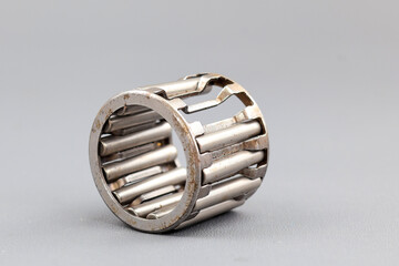 Damage a needle roller bearing is seen on a gray surface. The photo highlights the mechanical precision and metallic texture of the industrial part.