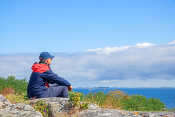 Young man sitting and resting during a hike in Finnish nature. Highlights outdoor adventure, relaxation, and connection with northern wilderness
