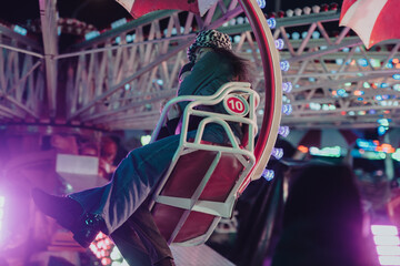 Vibrant scene of someone riding a fun fair attraction at night amid dazzling lights.
