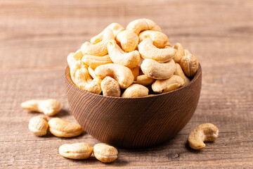 Organic roasted cashew nuts in a wooden bowl. Top view. 