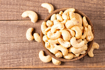 Organic roasted cashew nuts in a wooden bowl. Top view. 
