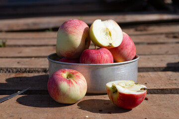 red and yellow apples on a wooden surface in the sunlight