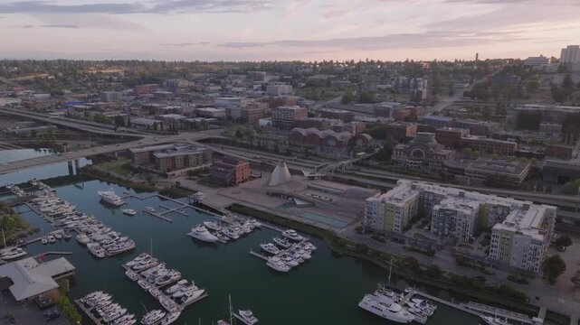 Aerial view of Thea Foss Waterway with boats, buildings, and a distinctive white structure under a soft sky, Tacoma, Washington, United States.