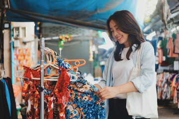Young Asian woman smiling happily while exploring a traditional fresh food market. Concept of healthy lifestyle, travel experience, and authentic local culture in Asia.