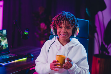 Teen boy smiling while engaging in video streaming activities with vibrant neon light atmosphere