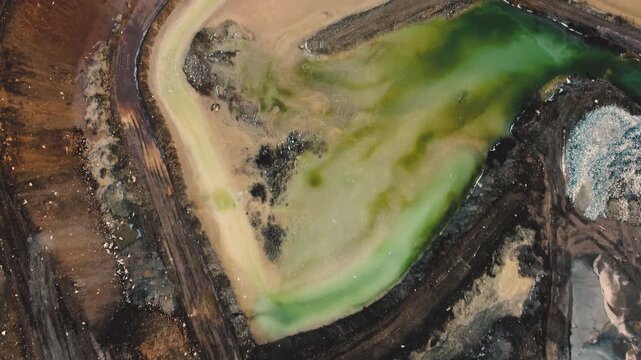 Drone fly over a gravel quarry with green and yellow water ponds - Concept of environmental impact