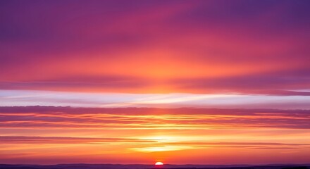 Obraz premium Vibrant orange and red clouds paint the evening sky as the sun dips below the horizon, casting a beautiful glow over the tranquil sea