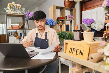 Small business florist flower owner shop working with laptop and notebook on accounting, finance and tax, entrepreneur focusing on paperwork, planning budget and organizing stock management tasks