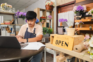 Small business florist flower owner shop lifestyle entrepreneur man focusing on laptop accounting, multitasking worker preparing finance paperwork, planning budget, recording tax data and bookkeeping