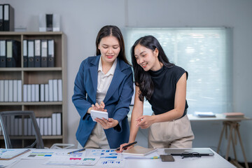Two women in business attire are looking at a tablet