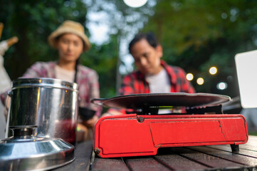 Indonesian southeast asian couple preparing for an outdoor meal, showcasing a portable stove and...