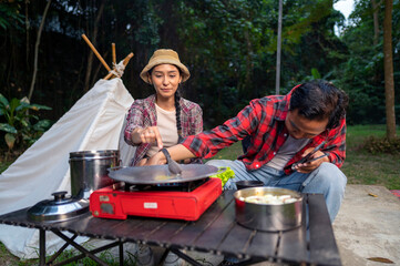 Indonesian southeast asian couple preparing for an outdoor meal, showcasing a portable stove and...