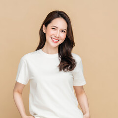 Obraz premium An Asian woman in a white t-shirt and shorts smiles warmly against a beige background, reflecting an easy summer style and casual comfort.