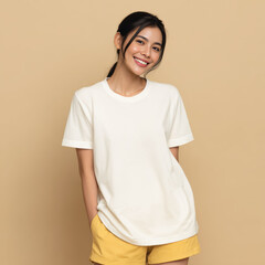 Obraz premium An Asian woman in a white t-shirt and shorts smiles warmly against a beige background, reflecting an easy summer style and casual comfort.