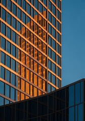 Modern glass skyscraper reflecting the sunset sky and surrounding buildings with a sleek architectural design and grid-like