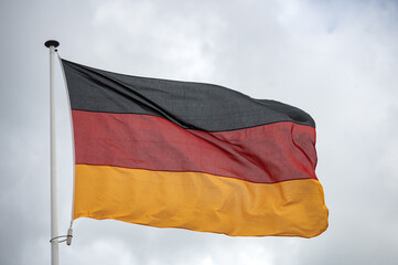 Germany flag fluttering in the wind with a blue sky and cloud background. 