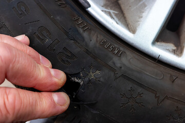 Car tire torn apart after riding on sharp road obstacles. Big hole on the side of the tyre