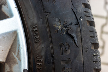 Car tire torn apart after riding on sharp road obstacles. Big hole on the side of the tyre