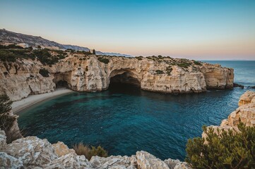 A series of coastal sea caves located along the southeastern shoreline, near a small fishing village harbor.