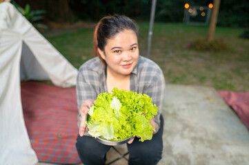 Indonesian southeast asian overweight woman holding a plate of vibrant and fresh green lettuce...