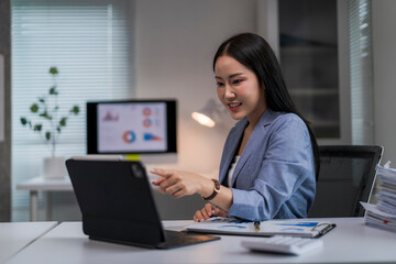 woman is sitting at a desk with a laptop and a monitor