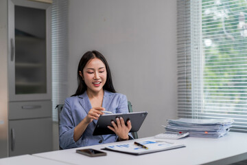 woman is sitting at a desk with a tablet in front of her
