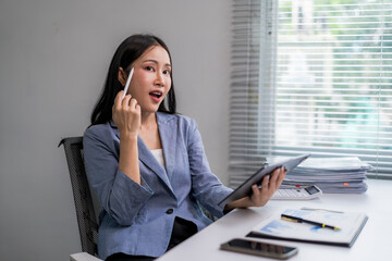 woman in a blue suit is holding a tablet and looking at it