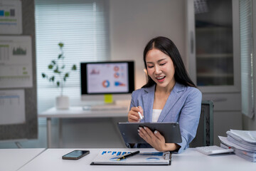 woman is sitting at a desk with a tablet in front of her