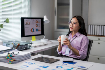 woman is sitting at a desk with a computer monitor and a cup of coffee