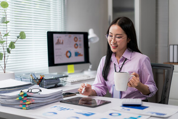 woman is sitting at a desk with a white mug in her hand